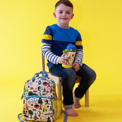 Menino com mochila infantil colorida e garrafa, fundo amarelo