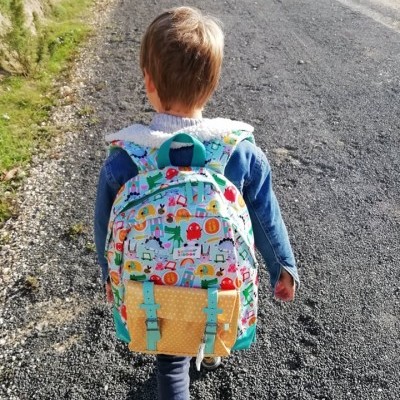 Criança com mochila colorida a caminhar numa estrada