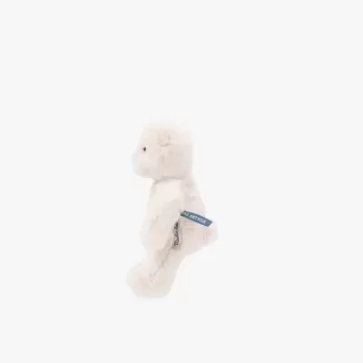 Ursinho de peluche branco com etiquetas azuis nas costas