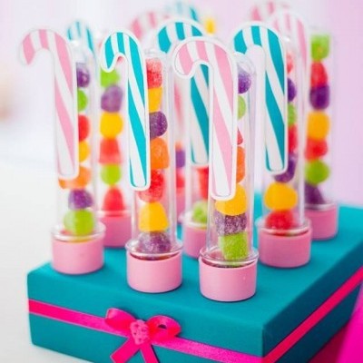 Tubo transparente com rebuçados coloridos e etiqueta de bengala de Natal em base azul com fita rosa