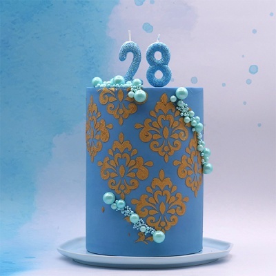 Bolo azul com padrão dourado e velas número 28.