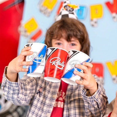 Copo de papel para festas Rally Championship azul e vermelho segurado por criança
