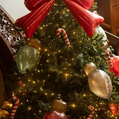 Árvore de Natal decorada com grandes laços vermelhos, bolas em forma de lâmpadas e doces bengala