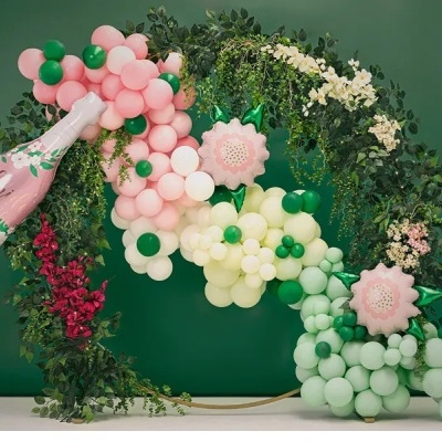 Arco decorativo com balões rosa, branco e verde e folhagem sobre fundo verde escuro