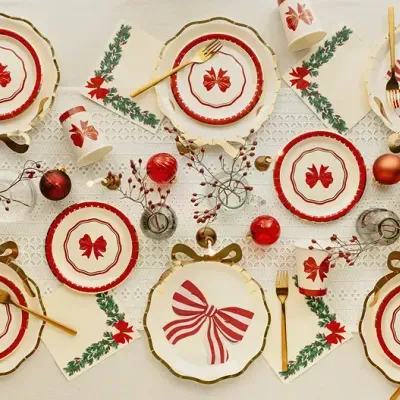 Mesa de Natal com pratos, copos, talheres dourados e decoração vermelha e verde