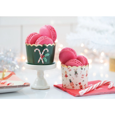 Macarons rosa em forminhas de papel natalícias sobre mesa branca com decoração de Natal