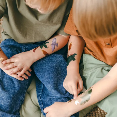 Crianças com tatuagens temporárias de dinossauros nos braços