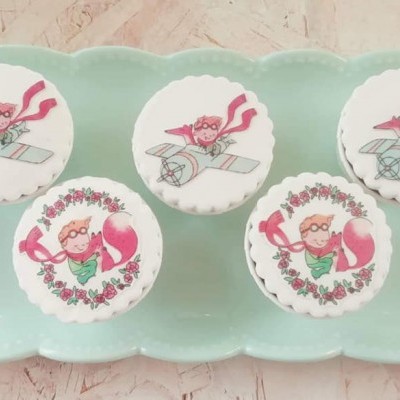 Cinco cupcakes decorados com glacê branco e imagens de uma personagem de desenho animado num prato verde