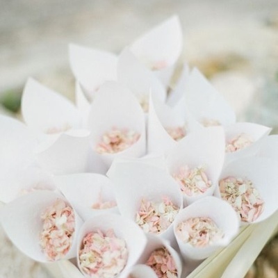 Cones de papel branco com pétalas de flores cor de rosa