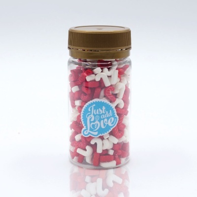 Frasco transparente com cápsulas vermelhas e brancas e etiqueta Just add Love