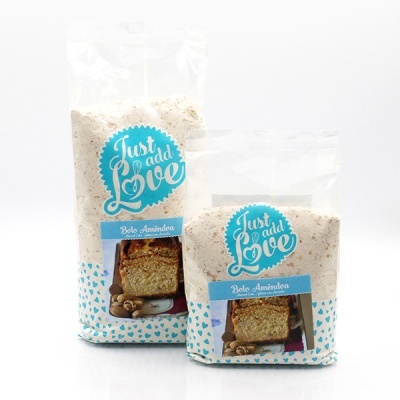 Embalagens de mistura para bolo amêndoa da Just Add Love com etiquetas azuis e padrão de corações azuis.