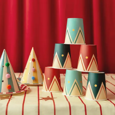 Vasos de papel coloridos com padrão geométrico empilhados sobre mesa com toalha riscada