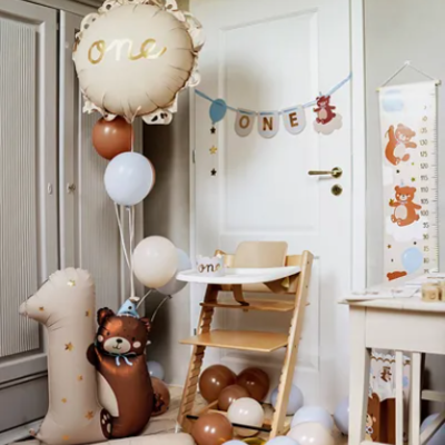 Decoração para aniversário de um ano com balões bege, castanho e branco e cadeira alta de madeira