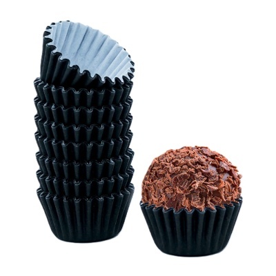 Formas pretas para doces empilhadas e brigadeiro com raspas de chocolate
