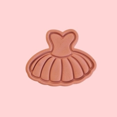 Moeda em bronze em forma de vestido de bailarina sobre fundo cor-de-rosa