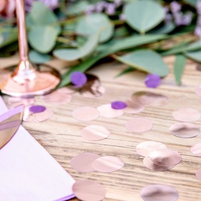 Mesa decorada com confetes, guardanapo branco, faca e copo rosa