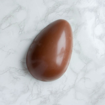 Ovo de chocolate castanho sobre superfície de mármore branco e cinzento
