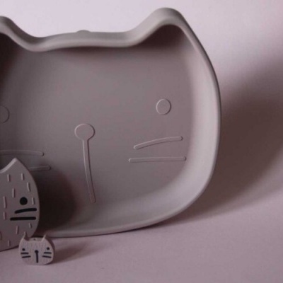 Prato cinzento em forma de gato com dois moldes pequenos iguais sobre fundo cinzento