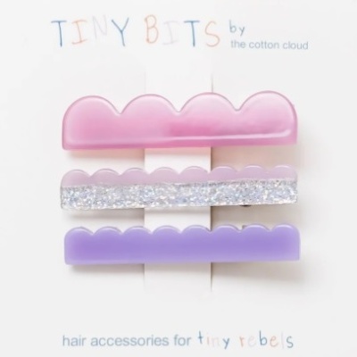 Três ganchos de cabelo em tons pastel rosa, prateado brilhante e roxo em cartão branco