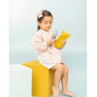 Menina pequena com roupa rosa e óculos segurando dois frascos em forma de animais