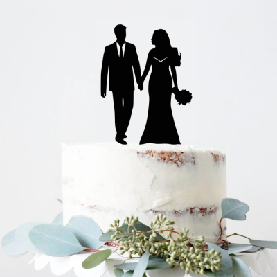 Bolo de casamento com topo decorativo de casal de noivos e folhas verdes na base