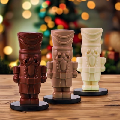 Três soldados de brinquedo de chocolate em diferentes cores com fundo decorativo festivo