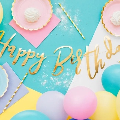Decoração de aniversário com pratos de papel, balões e letras douradas Happy Birthday