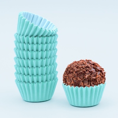 Forminhas de papel azuis empilhadas com brigadeiro numa das forminhas