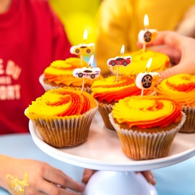 Cupcakes decorados com velas de carros e velocímetro em suporte branco