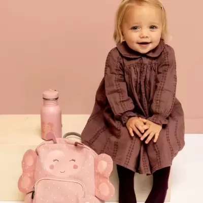 Criança sentada com mochila e garrafa rosa