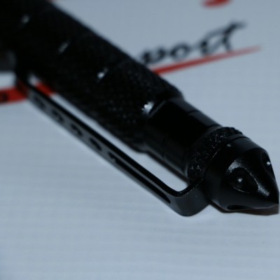 Caneta preta texturizada com clip sobre papel branco com letras vermelhas e pretas