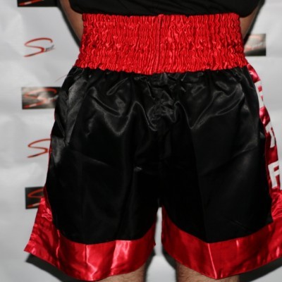 Calções de boxe pretos com cintura e barra vermelha.