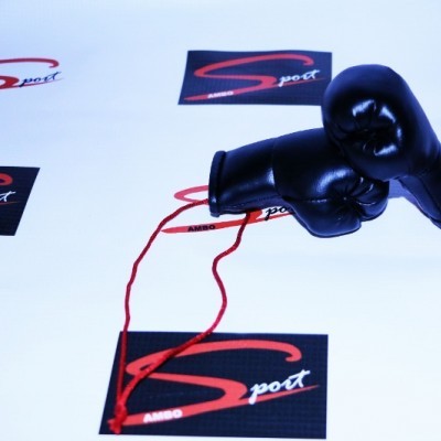 Par de luvas de boxe pretas com cordões vermelhos sobre cartazes com a palavra SPORT