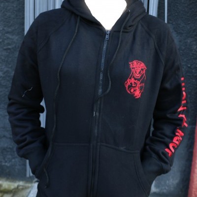 Casaco preto com capuz e padrão vermelho de pantera no peito e texto vermelho na manga com parede preta ao fundo