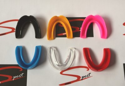 Protetores bucais coloridos sobre fundo com texto