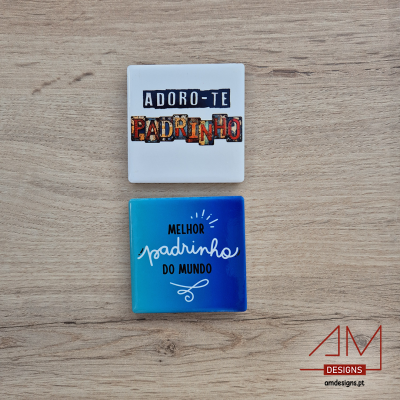 Dois ímanes quadrados com textos em português sobre uma mesa de madeira clara