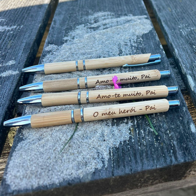 Canetas de bambu com textos gravados colocadas sobre madeira com areia