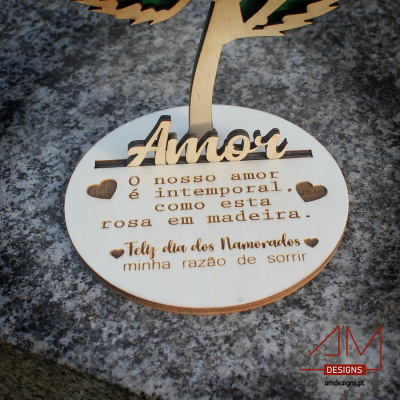 Base redonda de madeira gravada com texto sobre amor, com árvore decorativa, em superfície de pedra cinzenta
