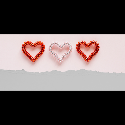 Três corações de molas metálicas coloridas em fundo creme