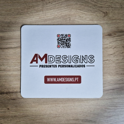 Cartão branco com texto AMD ESIGNS PRESENTES PERSONALIZADOS e código QR sobre superfície de madeira