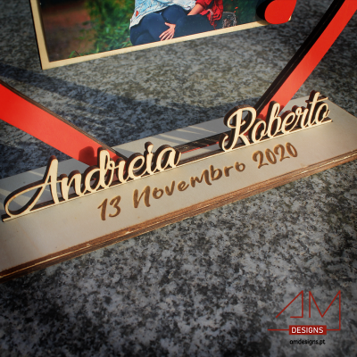 Base de madeira com nomes e data gravados, suporte vermelho e fotografia
