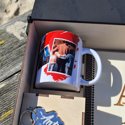 Caneca branca com imagens de pessoas numa caixa de madeira com porta-chaves azul e caderno