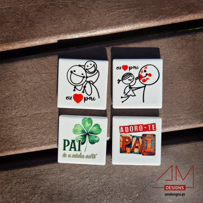 Quatro ímanes quadrados para o Dia do Pai com textos e desenhos coloridos sobre superfície castanha