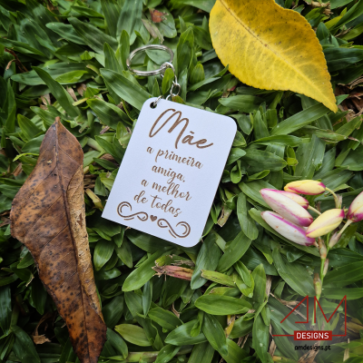 Chaveiro branco com texto em letra cursiva castanha sobre relva verde com folhas e flores