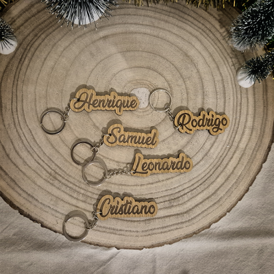 Chaveiros de madeira com nomes gravados sobre fatia de tronco de madeira com decoração natalícia