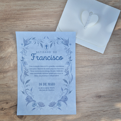 Convite azul de batizado com envelope branco em mesa de madeira