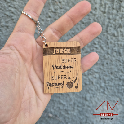 Porta-chaves de madeira gravado com texto para padrinho, segurado por mão contra parede cinza