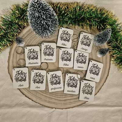 Porta-chaves de Natal brancos com textos em preto e decoração natalícia com pinheiros e uma fita verde e dourada.