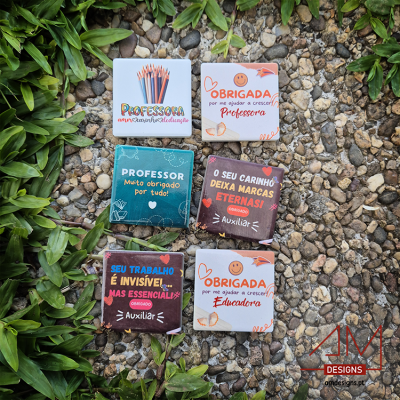 Embalagens coloridas de chocolates com mensagens de agradecimento para professores e auxiliares sobre pedras e folhagens.