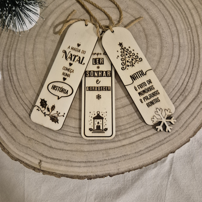 Três marcadores de páginas em madeira clara com motivos e texto de Natal em cima de madeira